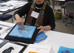 Artist-in-residence Marilyn Olsen discusses her hand embroidered birds with attendees